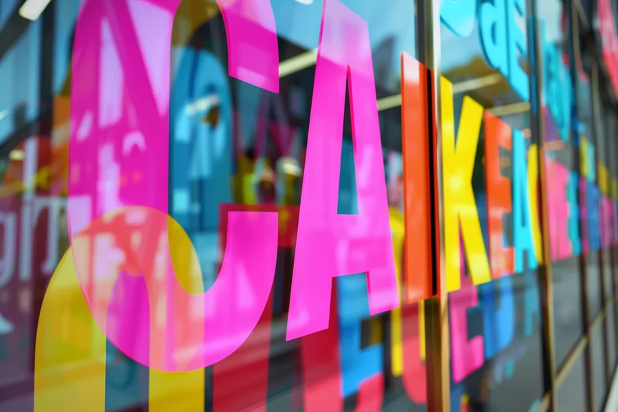 Bunt beleuchteter Schriftzug im Schaufenster eines Ladenlokals
